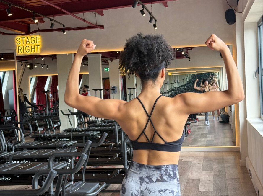 Lagree before and after: Elita flexing her back and arms in front of the Megaformers at Blood, Sweat & Tears, Angel